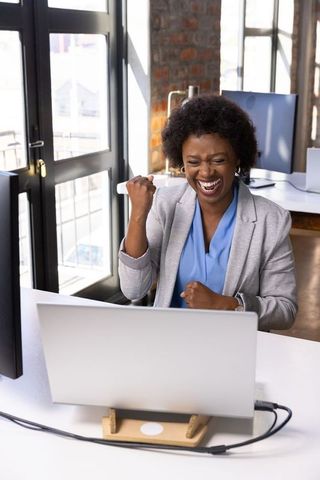 Joyful african american woman celebrating professional success in office