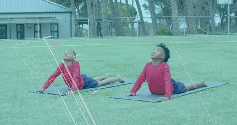 Young boys practicing yoga outdoors on green field