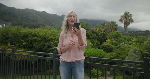 Mature Woman Enjoying Technology with Scenic Mountain View in Background
