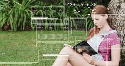 Young woman reading outdoors with futuristic hud overlay, relaxing beside tree on grass