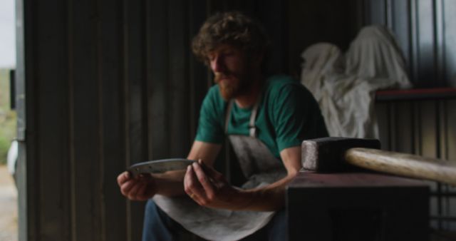 Artisan examining a handcrafted blade inside a workshop. Ideal for themes of craftsmanship, skill development, artisanal work, and handmade creations. Can be used in articles related to traditional skills, detailed handiwork, or craftsmanship tutorials.