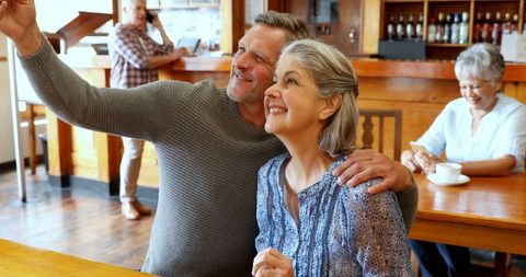 Caucasian Couple Taking a Selfie in Cozy Cafe with Warm Ambiance