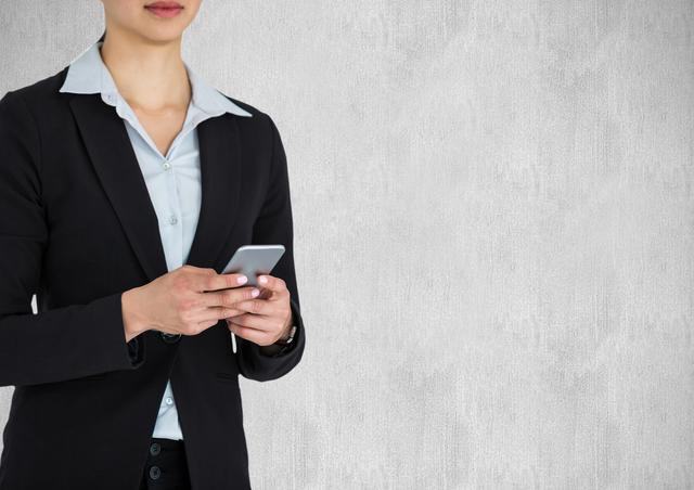 Digital composite of Midsection of businesswoman holding smart phone against wall