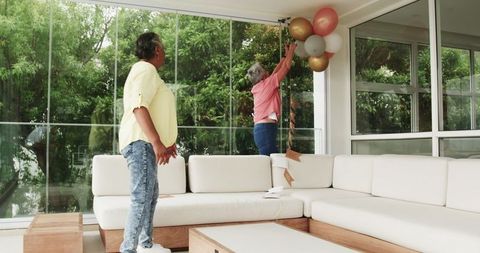Senior lesbian couple tidying up after birthday celebration at home