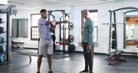 Trainer guiding shoulder stretch in modern gym environment