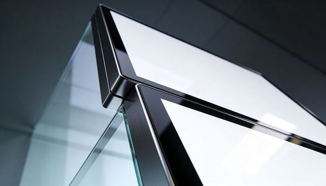 Tempered glass corner with brushed metal bezel revealing silicone sealant in showroom