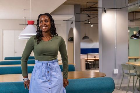 Smiling african american woman leaning on coworking booth in modern open-plan office