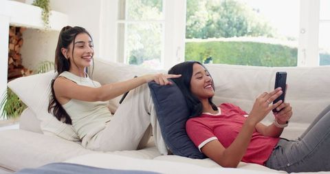 Happy Friends Relaxing on Sofa and Using Smartphone Lounge