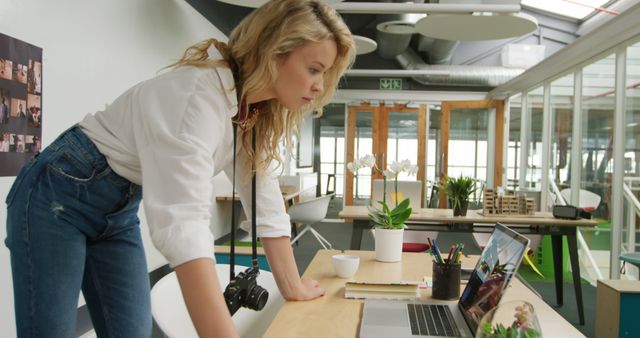 Female Photographer Looking at Laptop in Modern Office Space - Download Free Stock Images Pikwizard.com