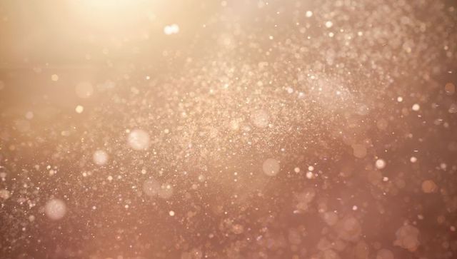 Floating golden glitter bokeh with shimmering dust and warm bronze glow