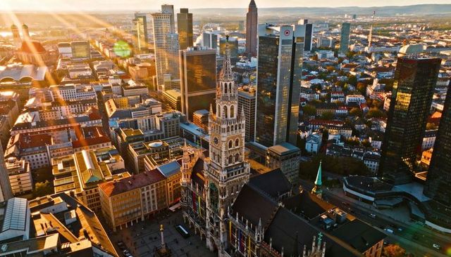 Golden-hour aerial showing gothic town hall tower dominating modern frankfurt skyline
