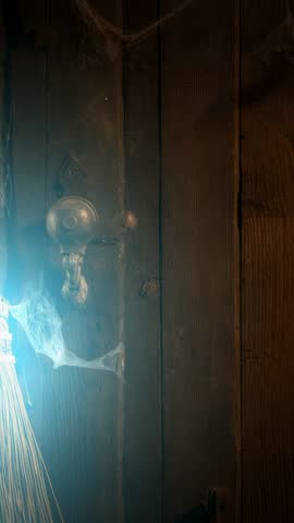 Vintage Doorknob and Broom Revealing Blue Glow in Cobwebbed Rustic Door Vertical Video