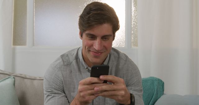 Man Smiling While Texting on Smartphone at Home - Download Free Stock Images Pikwizard.com