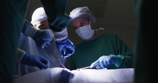Surgeons focus on intricate procedure under bright lights, sterile instruments at their service. Ideal for healthcare, medicine coverage, hospital presentations, medical-related blog posts, educational materials on surgery.