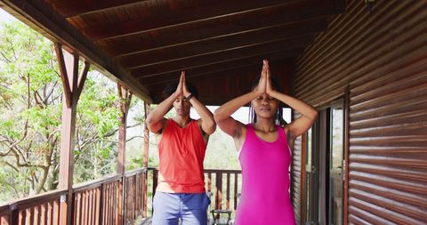 Couple Practicing Yoga on Rustic Cabin Balcony