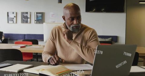 Senior professional reviewing financial reports on laptop in modern coworking workspace
