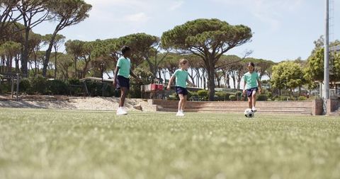 Youth girls passing soccer ball on park artificial turf during training