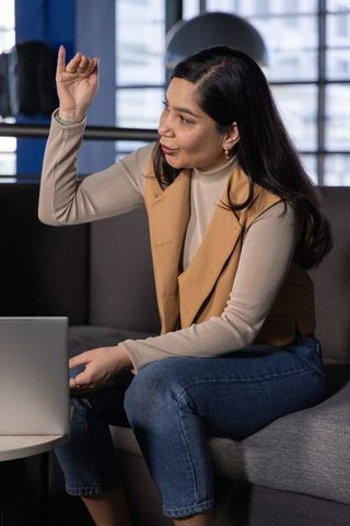 Asian businesswoman gesturing during virtual meeting in modern coworking lounge