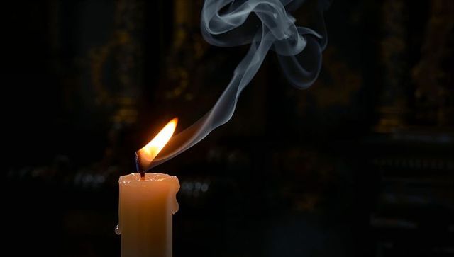 Dripping Candle Burning with Curling Smoke in Dark Interior for Ritual and Memorial