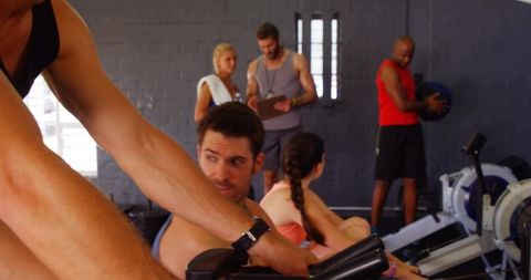 Group rowing workout training on ergometers with coach guiding and athletes pushing limits