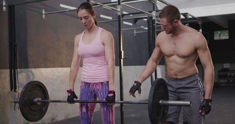 Woman engaged in weightlifting exercise under guide of shirtless trainer in a modern gym setting. Scene conveys strength, determination, teamwork. Suitable for illustrating gym training, personal motivation, or fitness program content. Useful for promoting healthy lifestyles or workout app advertisements.