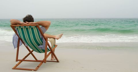 Man relaxing on sun lounger at tranquil beach