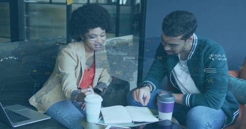 Colleagues collaborating over notebook and coffee with digital global data overlay
