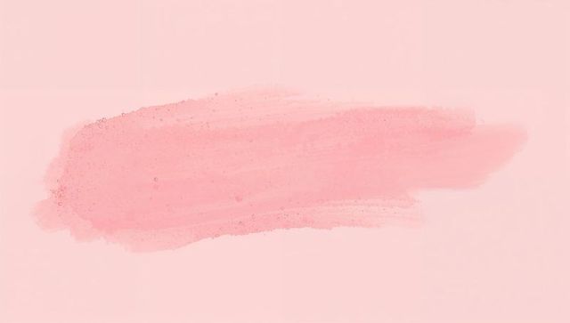 Displaying horizontal pink watercolor brush stroke on pale paper showing granulation droplets
