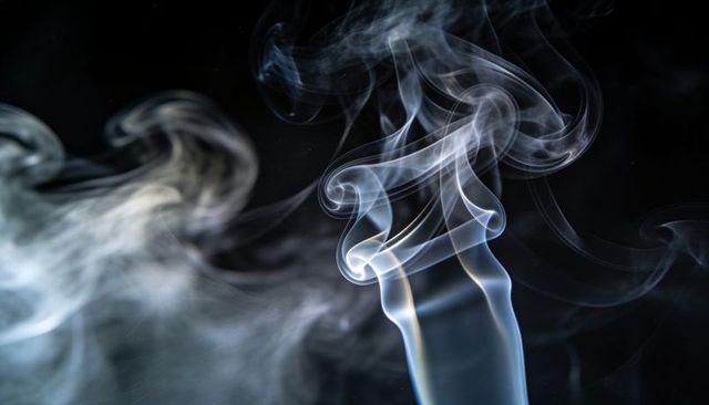 Smoke ribbons curling and spiraling upward in dark studio, translucent plumes and wisps