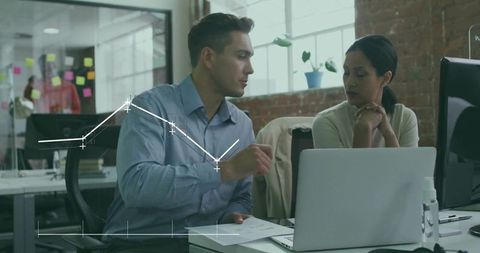 Team collaborating over laptop analyzing charts and documents in modern office