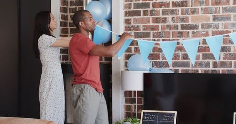 Happy friends decorating for baby shower in sunny living room