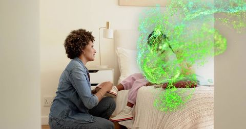 Kneeling caregiver comforting child on bed with green particle swirl suggesting calm