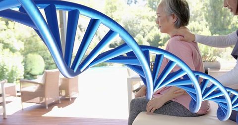 Blue DNA Helix Over Elderly Asian Woman Receiving Caregiver Support on Sunny Outdoor Patio