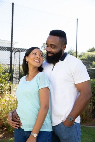 Smiling Diverse Couple At Tennis Court Gaze Lovingly