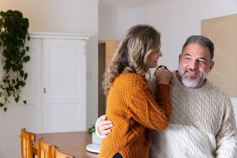 Mature couple sharing warm domestic moment in cozy knit sweaters at home