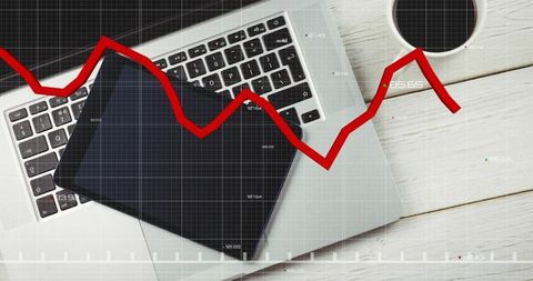 Digital workspace with laptop tablet and red trend line overlay for finance analytics