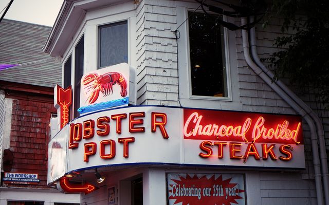 Retro neon sign showing entrance of Lobster Pot and Charcoal Broiled Steaks restaurant. Ideal for themes related to seafood, dining, vintage establishments, and capturing nostalgic Americana. The image can be used in travel magazines, restaurant reviews, marketing materials, and storytelling involving iconic dining spots.