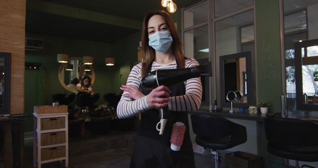 Young Hairdresser Wearing Protective Mask in Salon with Hairdryer - Download Free Stock Images Pikwizard.com