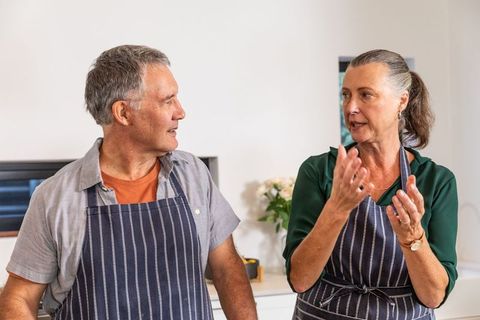 Senior Couple Cozy Chat in Modern Kitchen Wearing Aprons