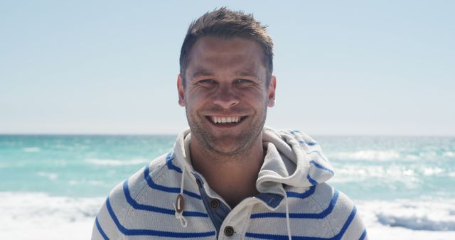 Smiling Man in Striped Hoodie Enjoying Beach on Clear Day - Download Free Stock Images Pikwizard.com