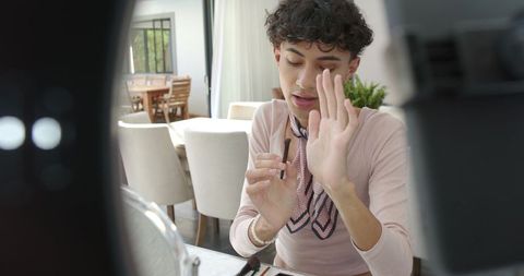Male beauty influencer filming makeup tutorial at home