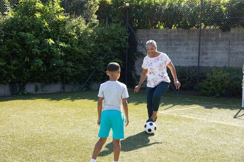 Grandmother Playing Soccer with Grandchild on Turf Field
