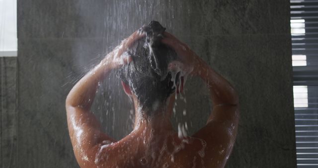 Person engaging in hair washing routine in a modern shower. Ideal for themes around personal hygiene, self-care, beauty routines, and bathroom products promotions.