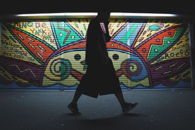 Silhouette of Man Walking Against Colorful Street Graffiti - Download Free Stock Photos Pikwizard.com