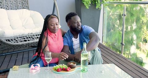 Romantic Couple Enjoying Wine and Fruit on Sunny Balcony Retreat