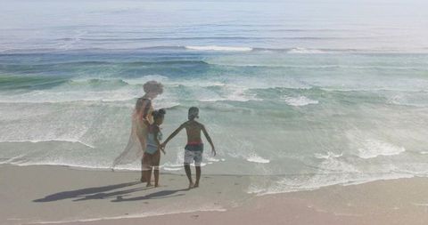 Double exposure standing woman and children watching ocean waves at sandy shoreline