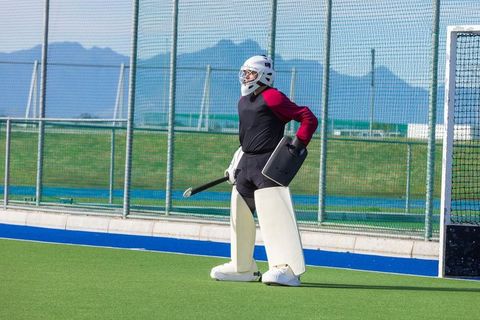 Field hockey goalkeeper in protective gear on field