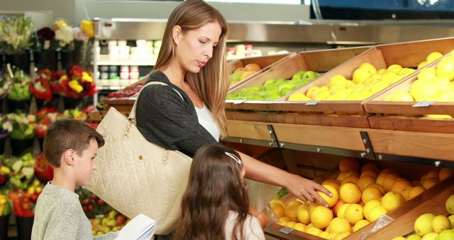 Mother picking fresh produce with children at grocery store. Family selecting lemons and healthy fruits, emphasizing nutritional choices. Ideal for illustrating family bonding, shopping habits, organic lifestyle promotions, healthy eating adverts or supermarket brochures.