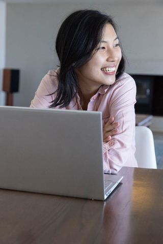 Cheerful woman working remotely on laptop in home office