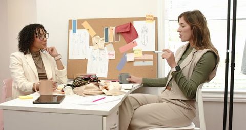 Fashion design team reviewing moodboard and fabric swatches at bright studio desk